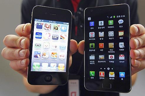 An employee of South Korean mobile carrier KT holds an Apple Inc's iPhone 4 smartphone and a Samsung Electronics' Galaxy S II smartphone as he poses for photographs at a registration desk at KT's headquarters in Seoul http://fastncurious.fr/wp-content/uploads/2012/02/apple-samsung-jo-yong-hak.jpg